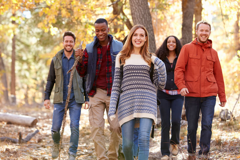 Group of happy friends hiking together through a forest